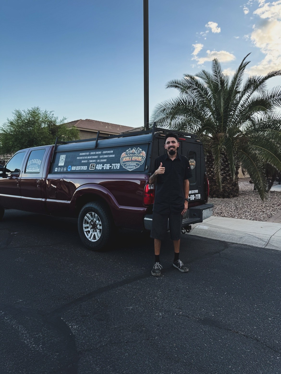 Ivan giving a thumbs up beside Estradas Garage’s branded red mobile service truck