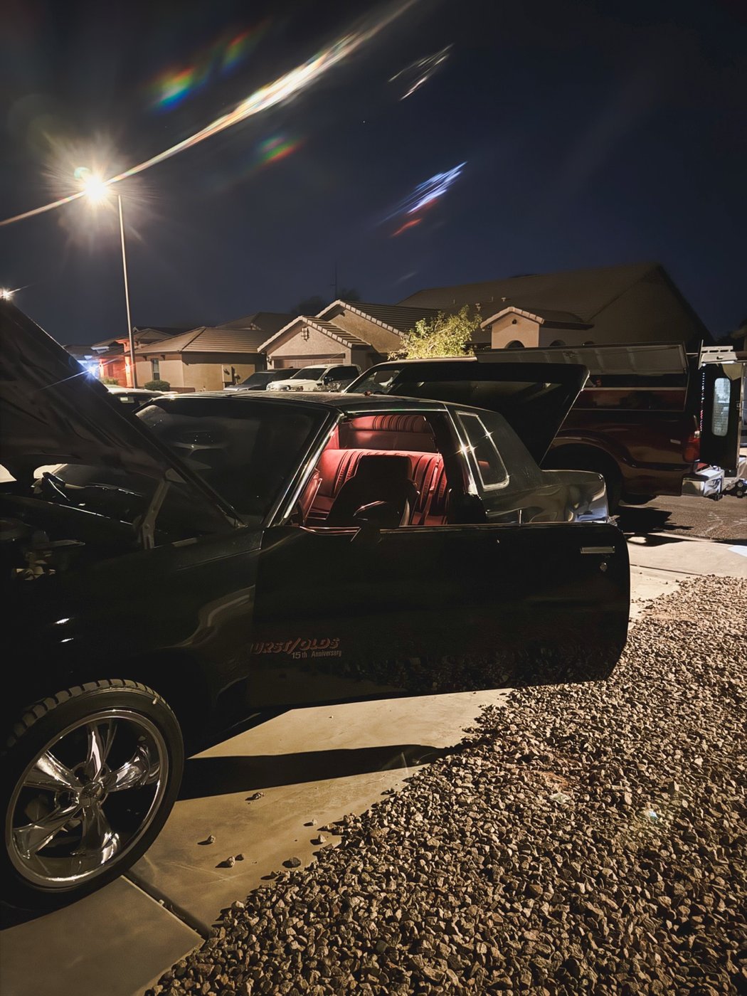 Black classic Oldsmobile being serviced at night