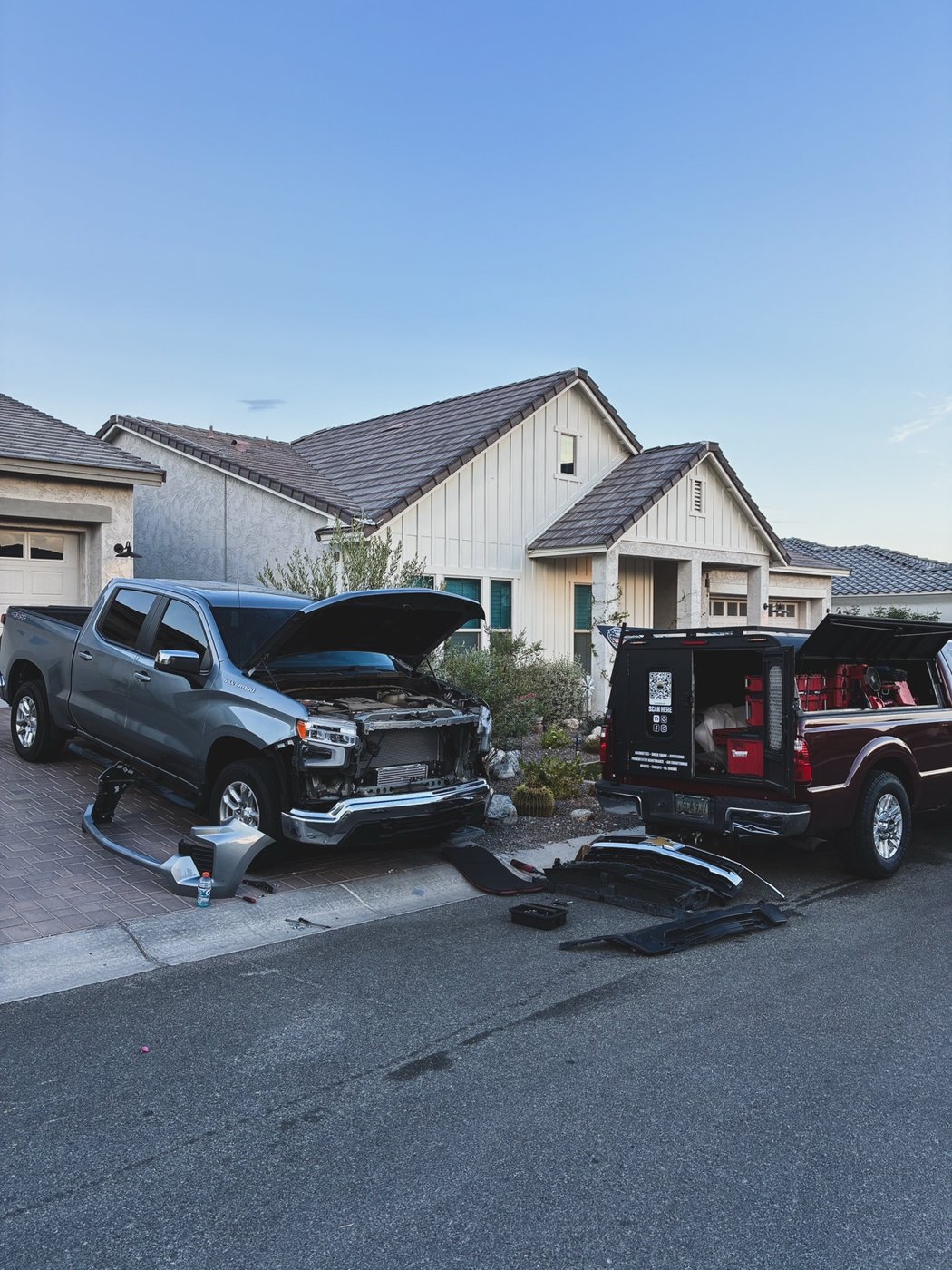 Silver Chevrolet truck receiving front-end work beside the Estradas Garage mobile service truck