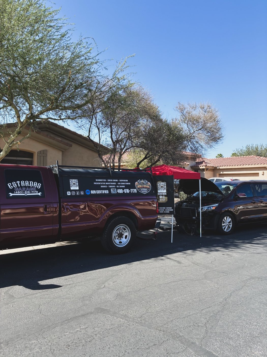 Branded Estradas Garage work truck set up at a mobile job site with a red canopy
